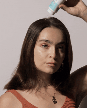 Woman applying Acure's Dry Shampoo for a fresh look